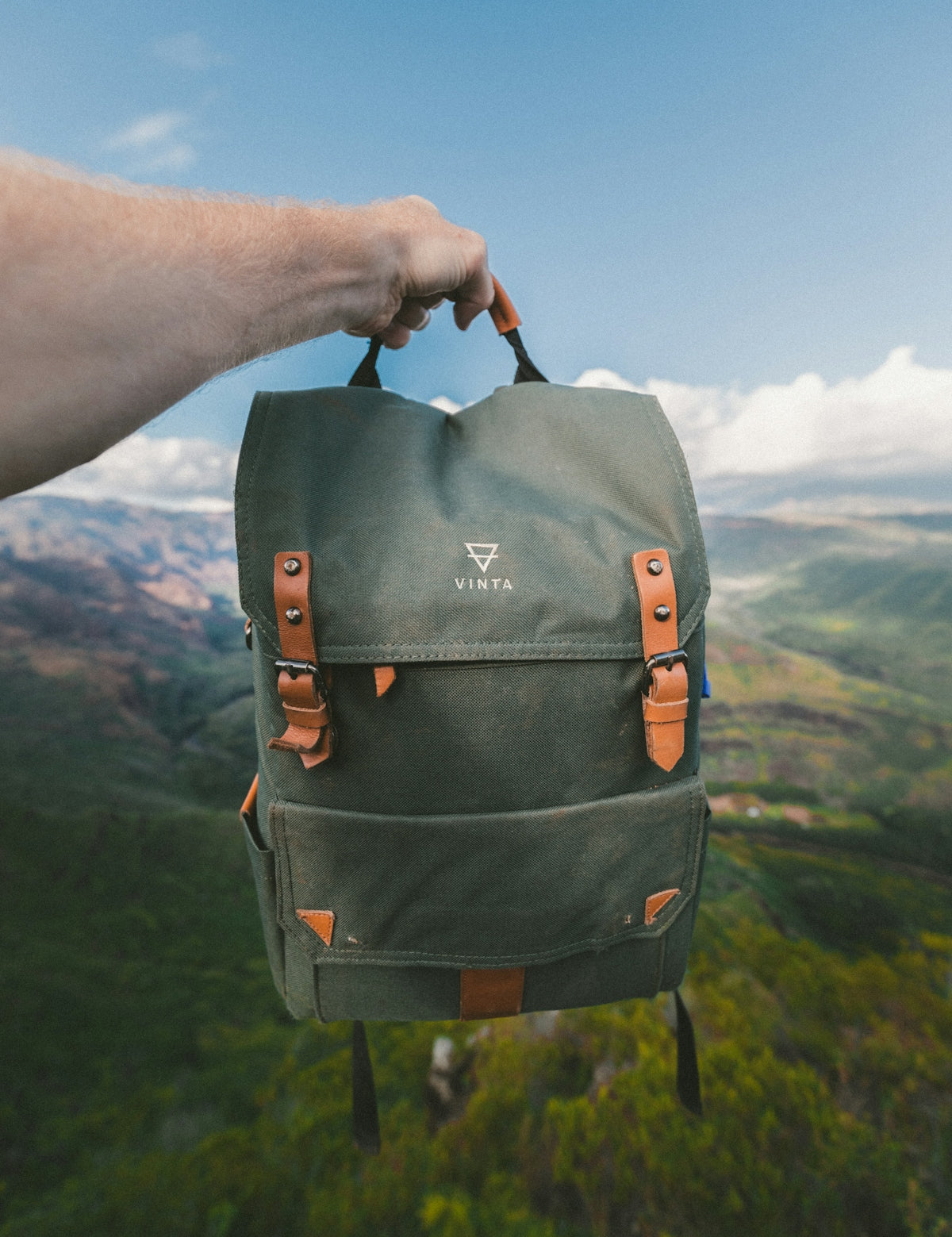 person holding black and brown Vinta backpack
