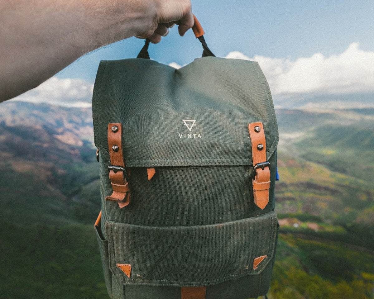 person holding black and brown Vinta backpack