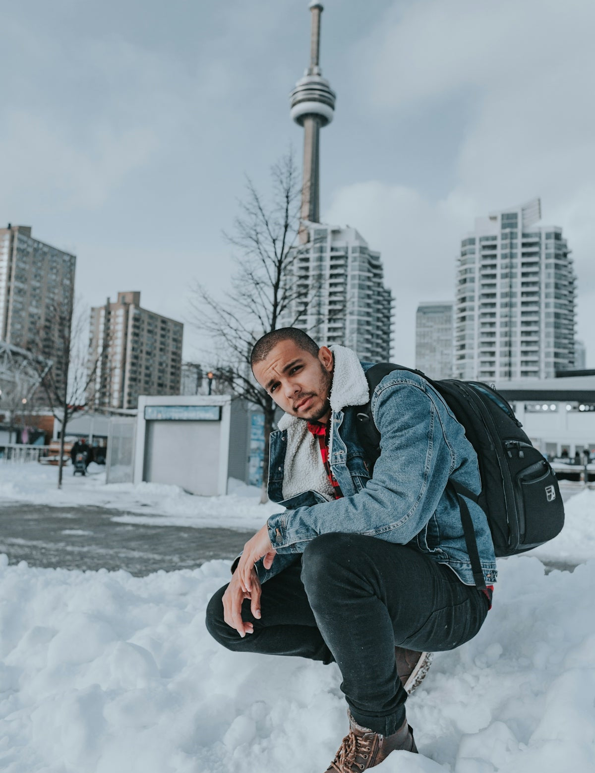 a man kneeling in the snow with a backpack