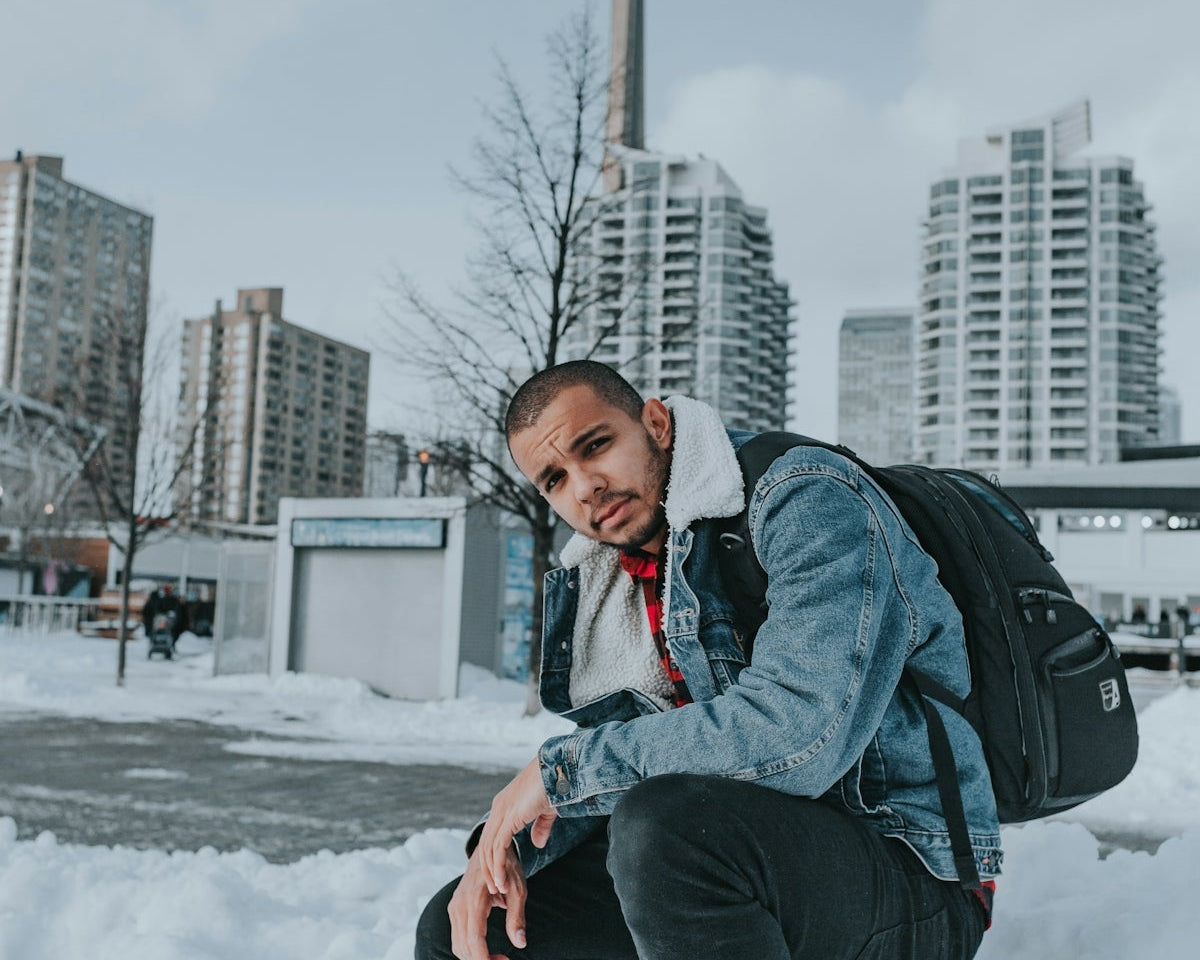 a man kneeling in the snow with a backpack
