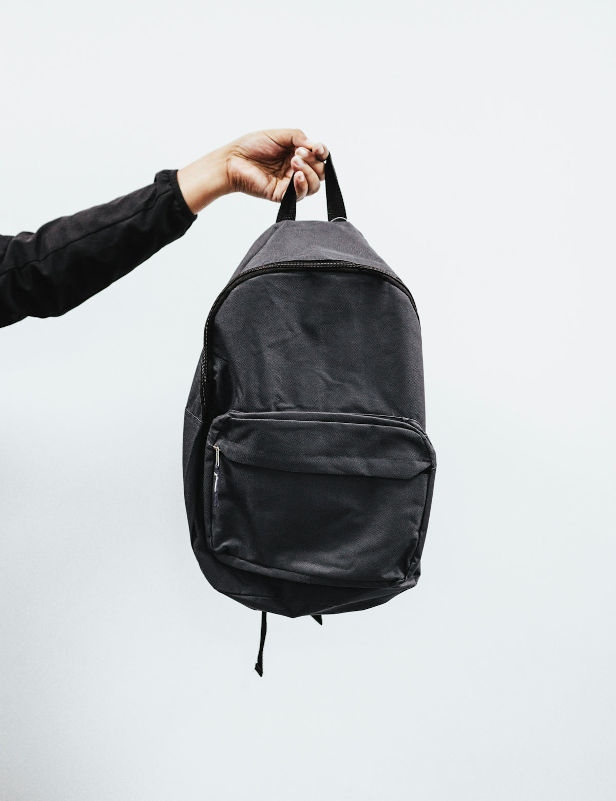 person in black jacket holding black backpack