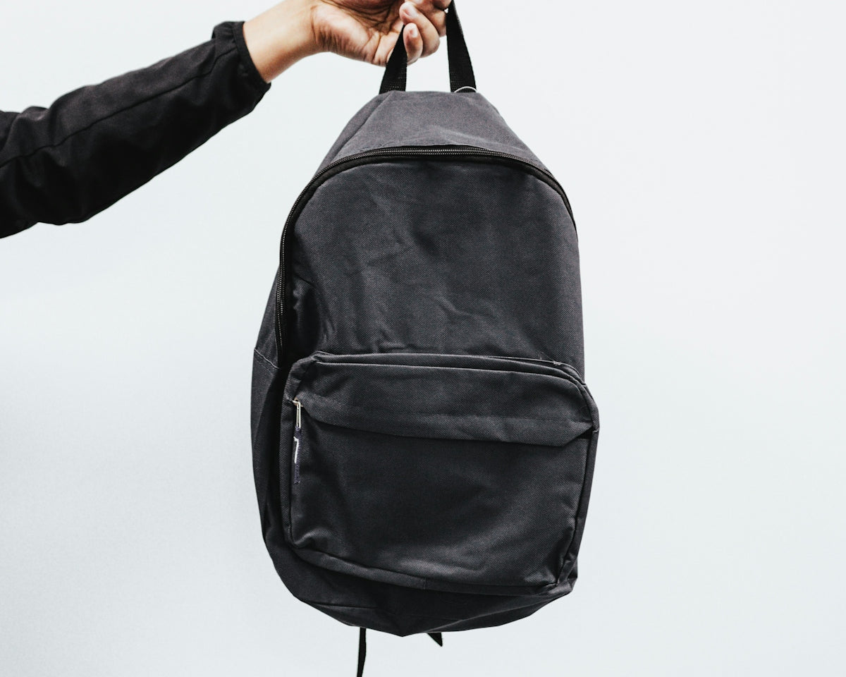 person in black jacket holding black backpack