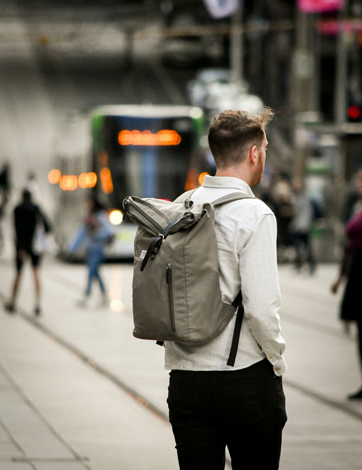 man in white dress shirt and black pants carrying black backpack walking on sidewalk during daytime