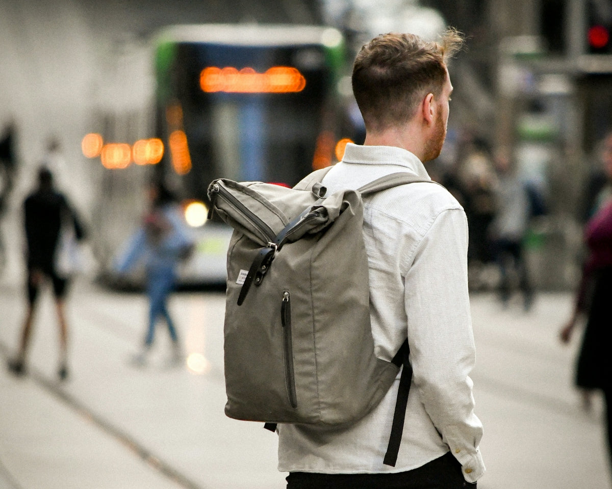 man in white dress shirt and black pants carrying black backpack walking on sidewalk during daytime