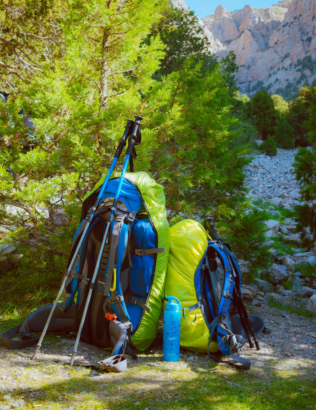 blue and black hiking backpacks on gray rocky ground
