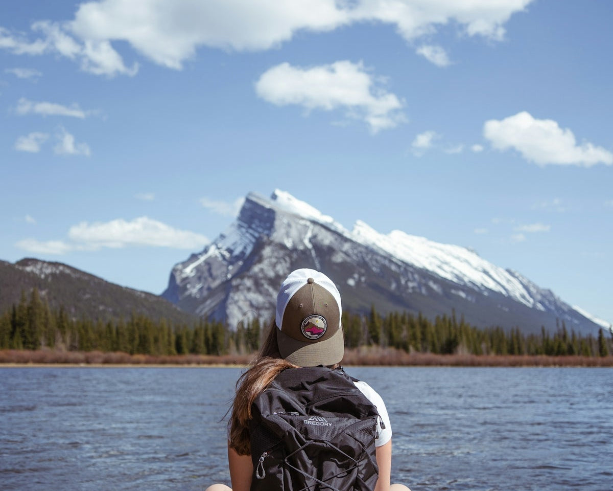 person in black and white backpack sitting on white wooden dock during daytime