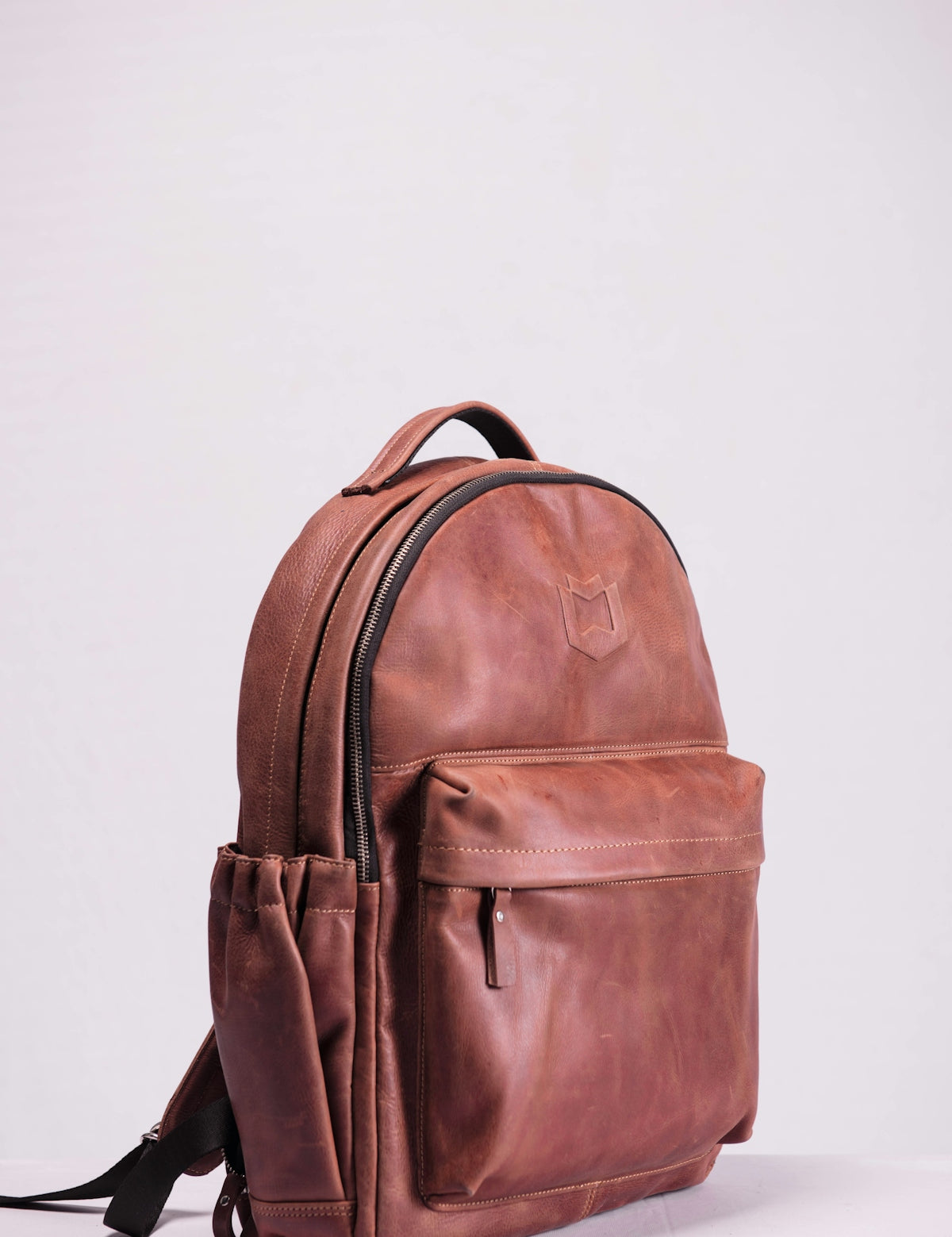 brown leather backpack on white wall