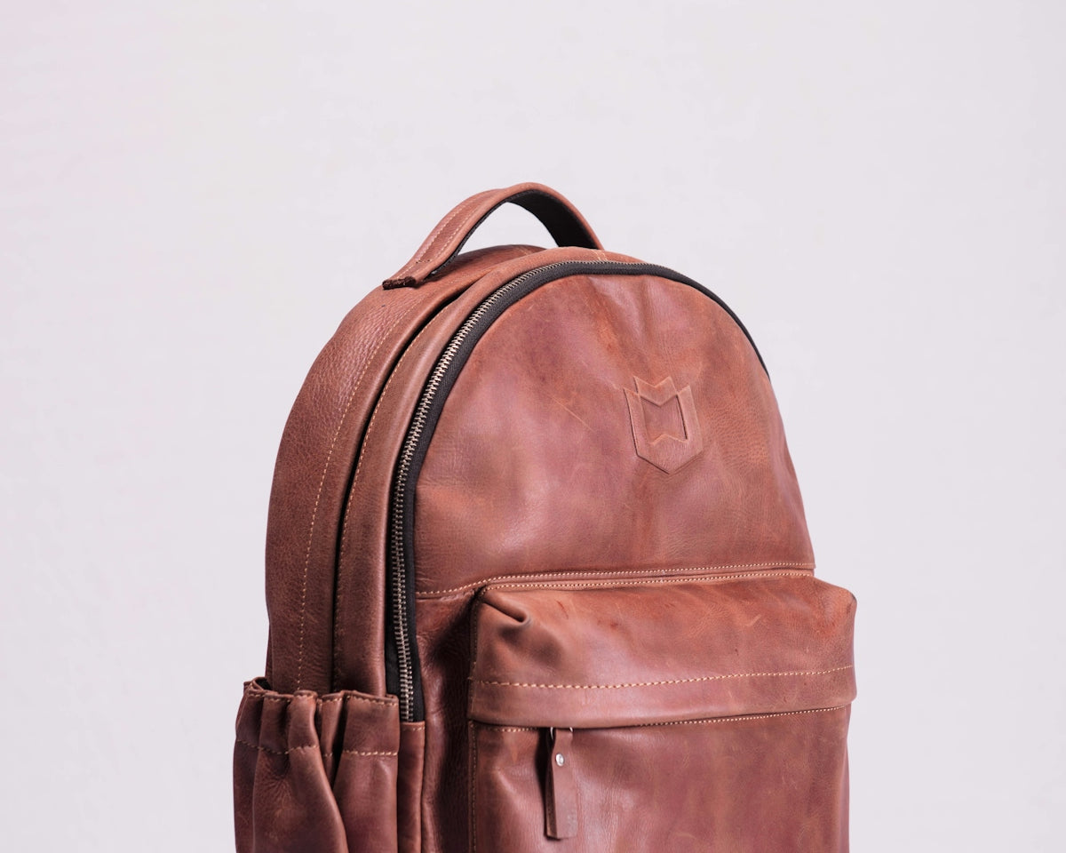 brown leather backpack on white wall