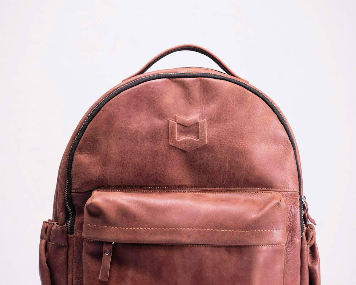 brown leather backpack on white surface