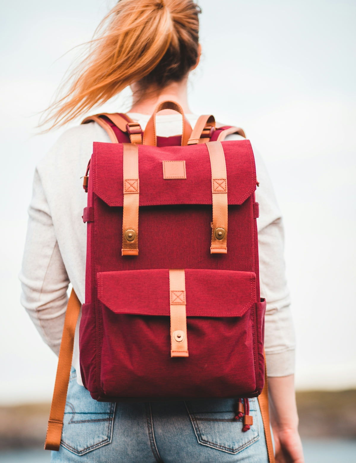 woman in white long sleeve shirt with red and black backpack