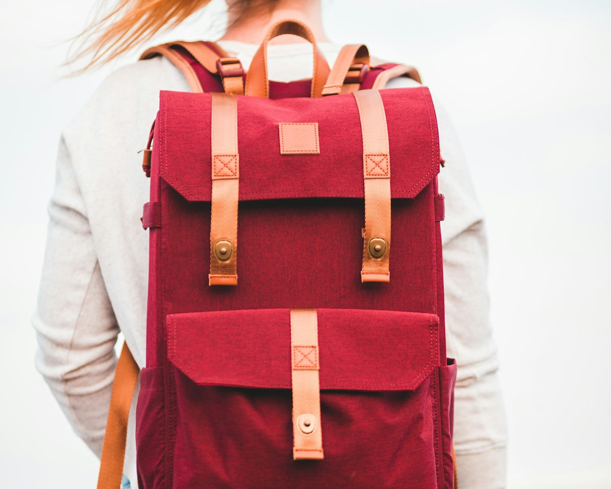 woman in white long sleeve shirt with red and black backpack