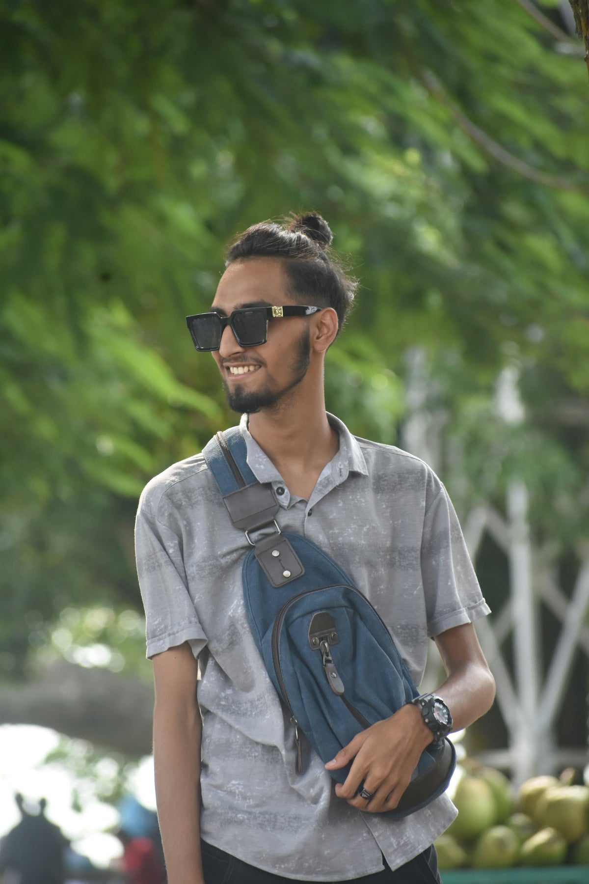 a man wearing sunglasses and carrying a blue bag