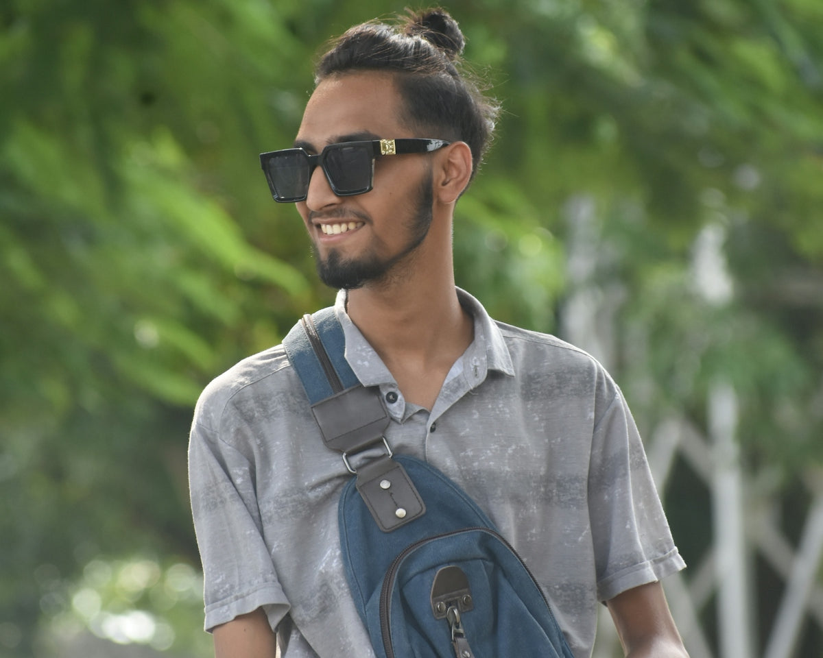 a man wearing sunglasses and carrying a blue bag