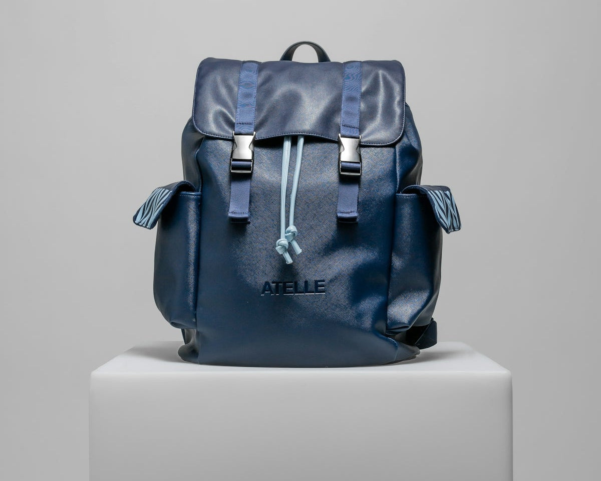 a blue backpack sitting on top of a white pedestal