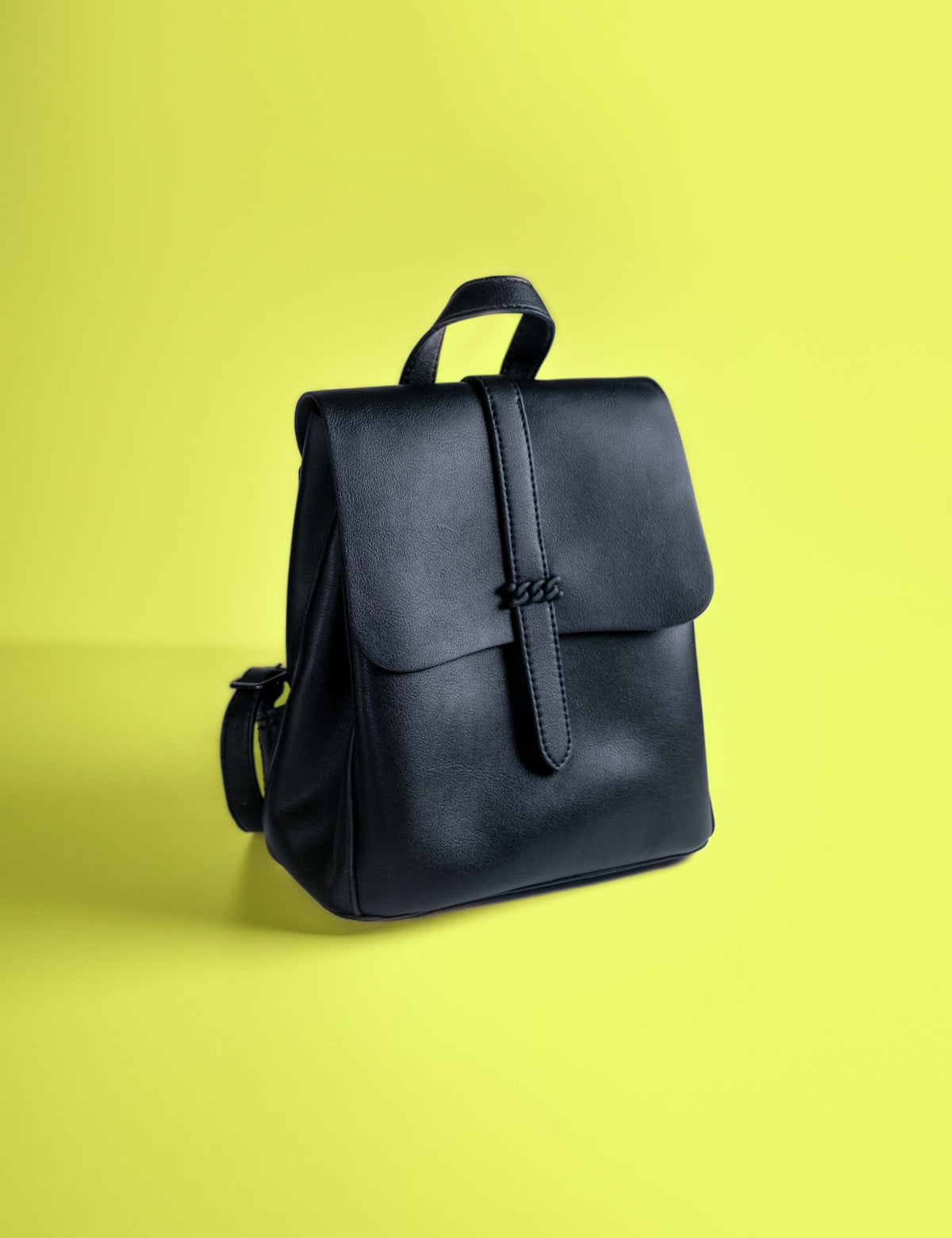 a black leather backpack on a yellow background