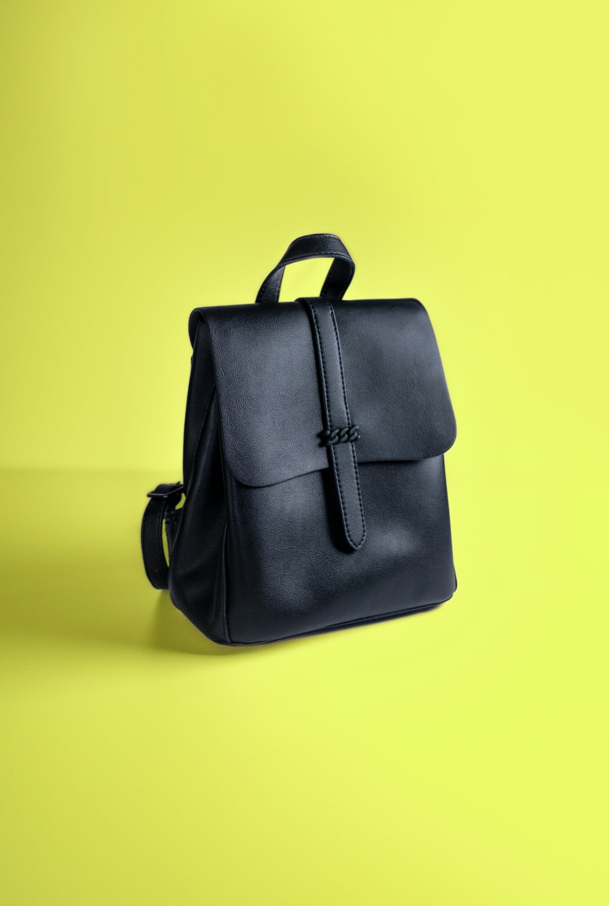 a black leather backpack on a yellow background