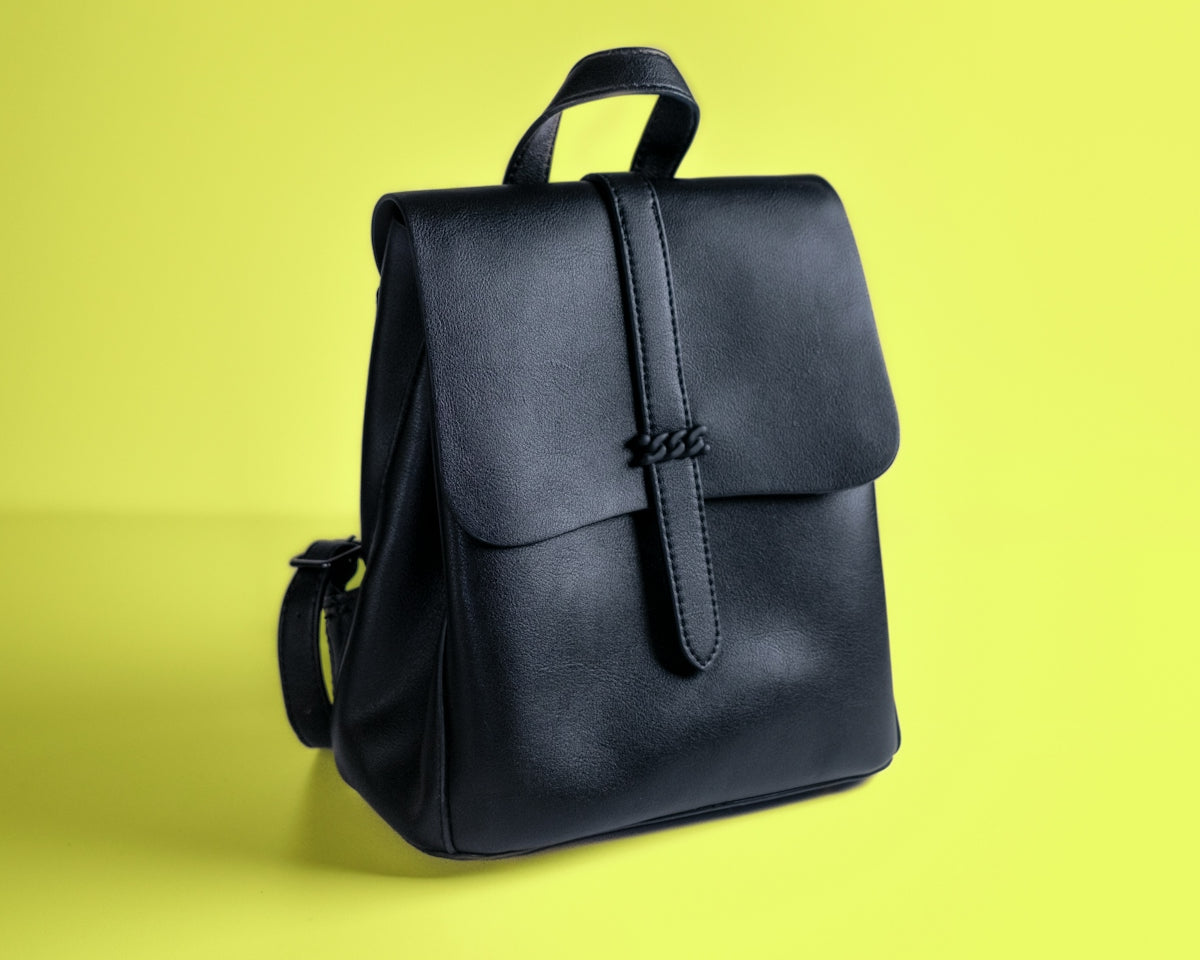 a black leather backpack on a yellow background