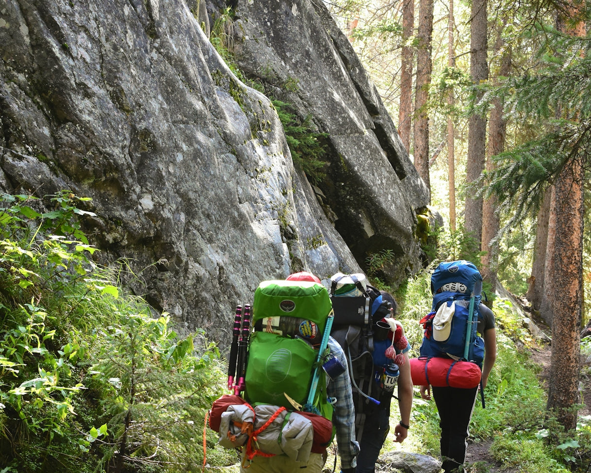 a group of people with backpacks walking up a trail
