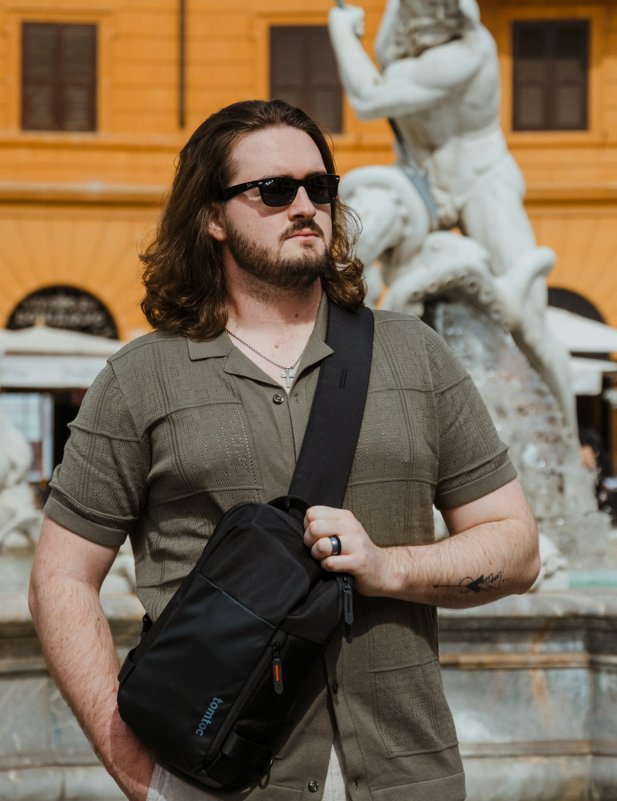 a man standing in front of a fountain holding a black bag